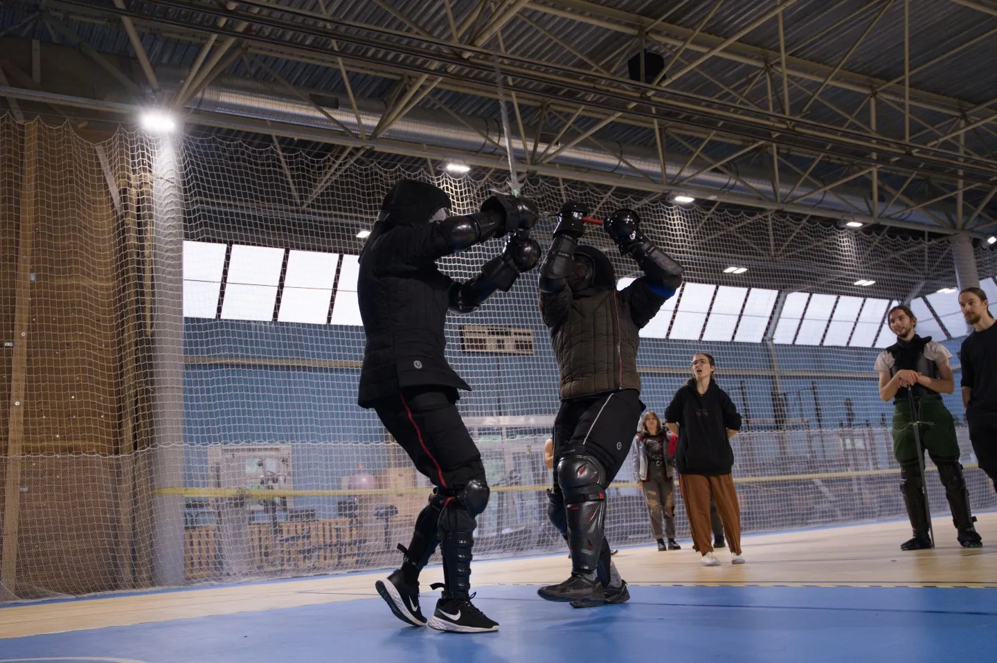 Du fechtuotojai susiremia kalavijais iš arti sporto salėje